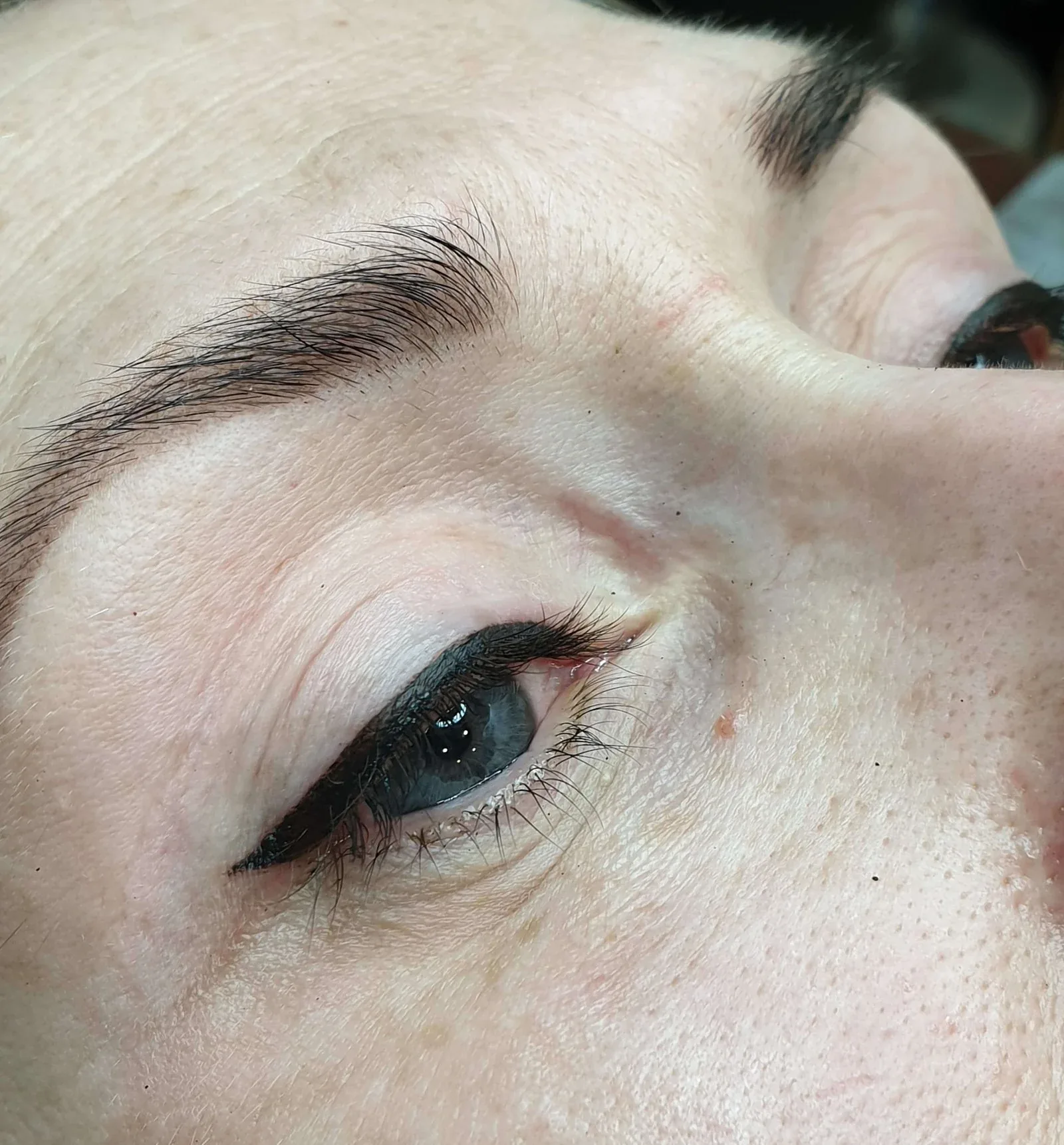 Permanent eyeliner with a bold winged flick along the upper lash line