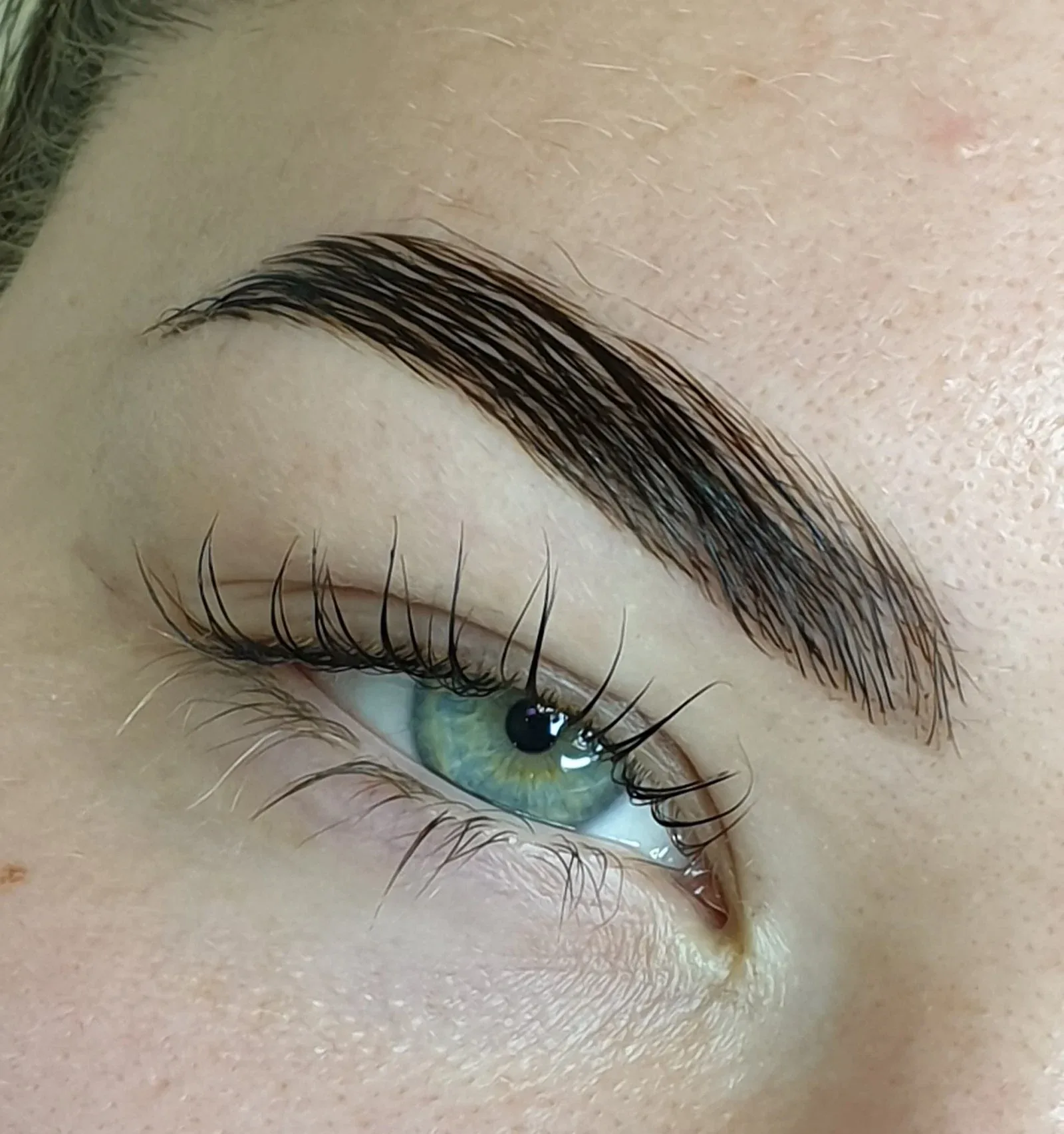Lash lift with a tinted brow, showing lifted lashes framing green eyes