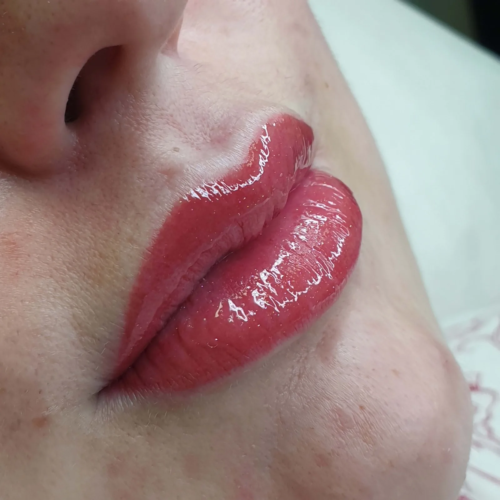 Freshly applied lip blush in a warm rose shade, shown from the side with a glossy finish